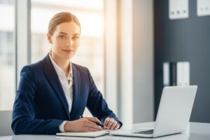 Młoda bizneswoman w granatowym garniturze przygotowuje się do rozmowy kwalifikacyjnej przy biurku w biurze